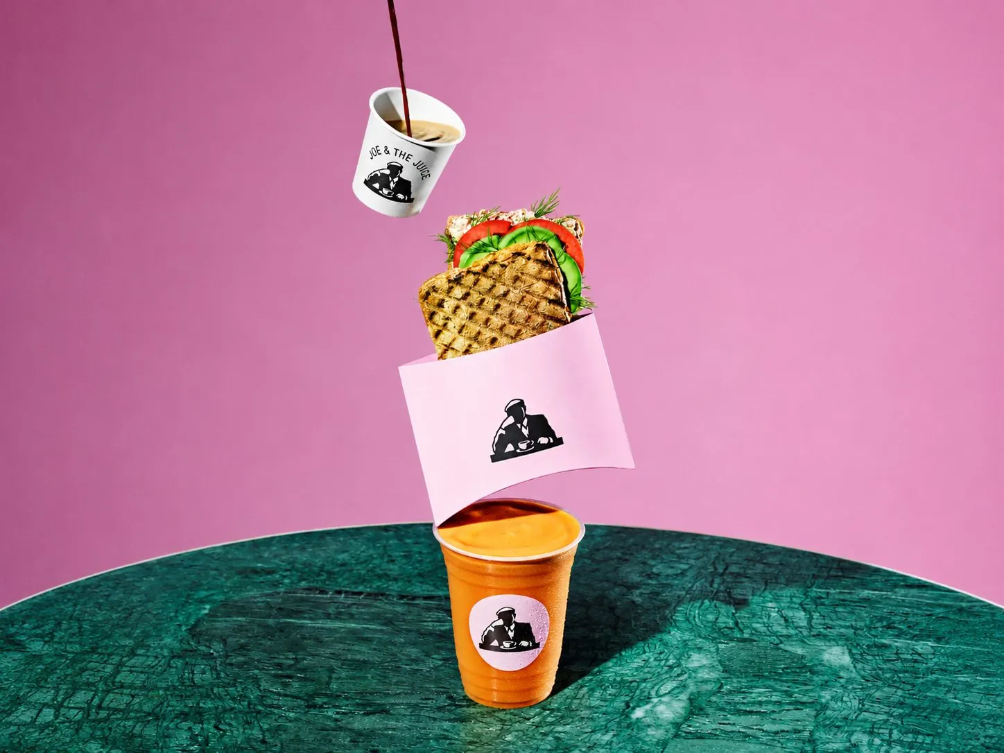 Joe & The Juice coffee and sandwich styled on pink